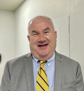 Declan Sheehy, wearing a gray suit, beams.