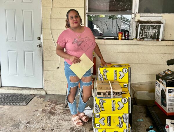 Sheysa Romero Santos poses with one hand on a stack of construction materials.