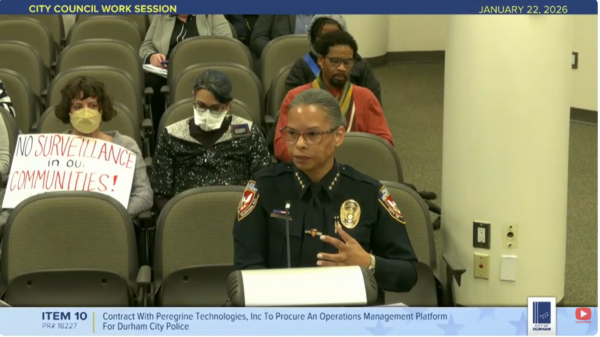 Screenshot of public meeting with police chief speaking at dias
