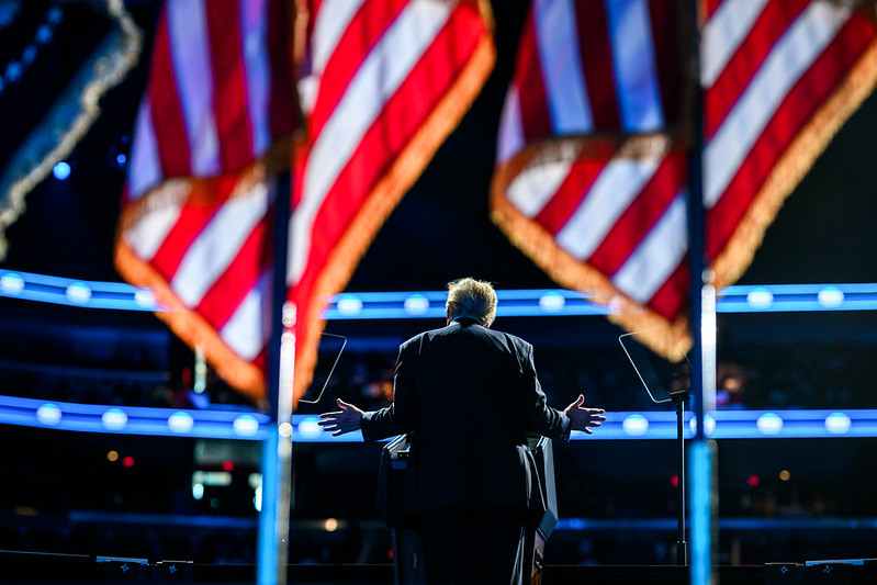 Trump Backside President Donald Trump stands at a lecturn viewed from behind and framed by American flags during the America Business Forum Miami in Miami, Florida.