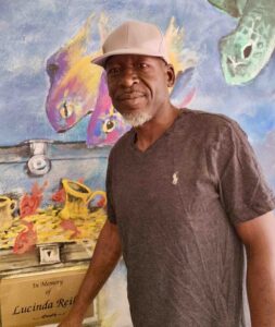 A man stands facing the camera in front of an ocean mural.