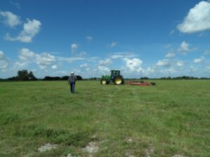A man walks toward a tractor in a field.