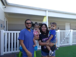 Two adults holding two young children smile at the camera