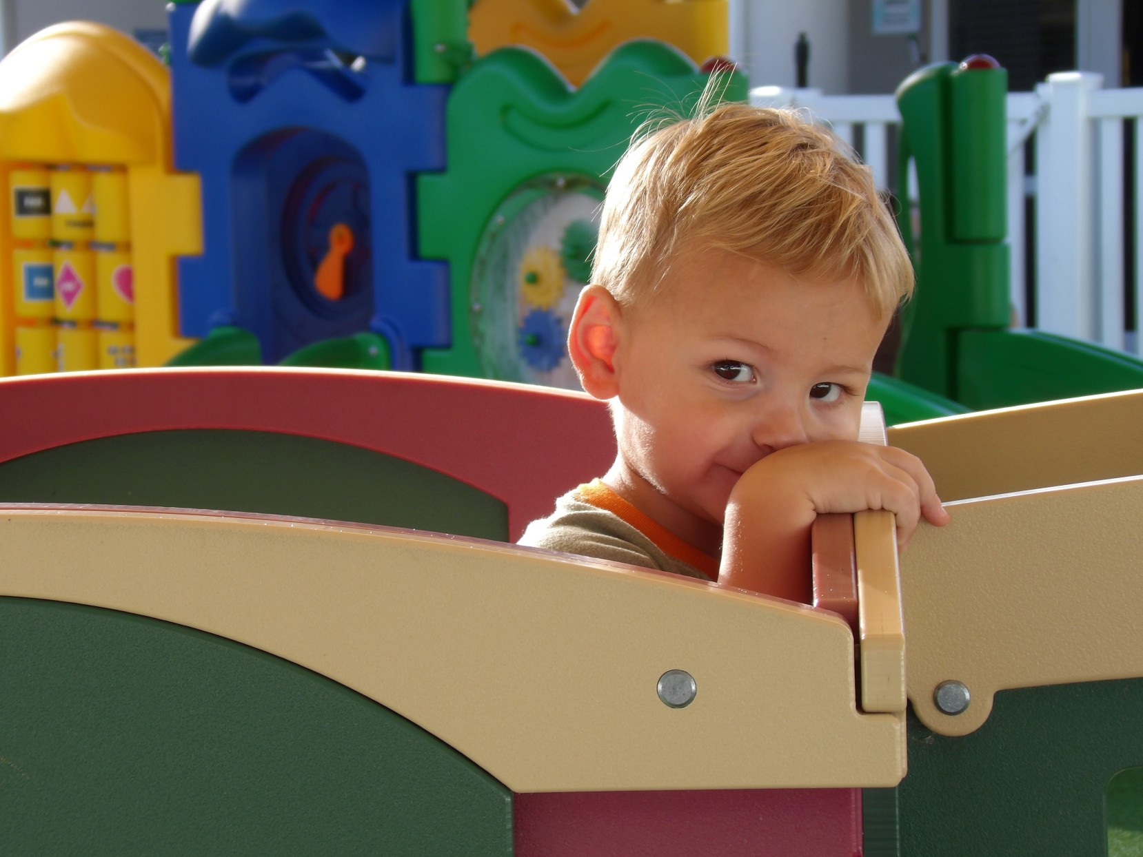 Owen Vaughan (1) A toddler is leaning his head on the side of a playset and looking at the camera