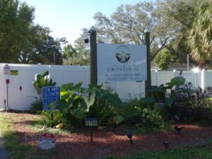 A sign advertising The Crossings sits in front of a fence.